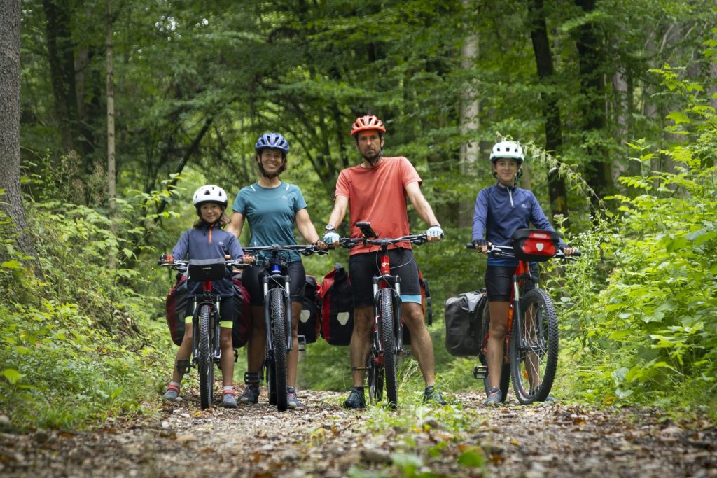 Águeda Monfort, Noel Arraiz y sus dos hijas en bicicleta por un bosque de los Alpes